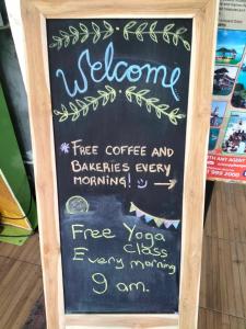 a chalkboard sign with a welcome tree coffee and dandelions every morning at Phangan Barsay Hostel in Thongsala