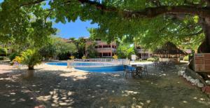 basen ze stołami i krzesłami pod drzewem w obiekcie Paradis Mimies Apartment w mieście Boca Chica