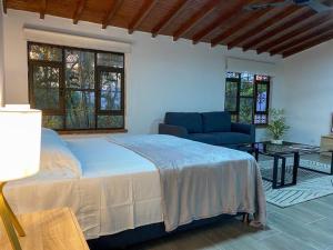1 dormitorio con cama, sofá y ventanas en Palos Altos en Medellín