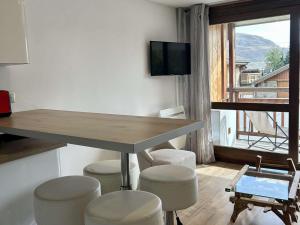 ein Raum mit Tisch und Hockern und einem Fernseher in der Unterkunft Charmant Studio 4p avec Terrasse Sud – Proche Pistes & Commerces – Alpe d'Huez - FR-1-405-339 in Huez