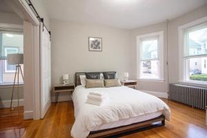 a bedroom with a large white bed with two windows at 2 bedroom condo close to Boston and Cambridge with free parkings in Boston