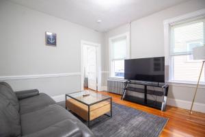uma sala de estar com um sofá e uma televisão de ecrã plano em 2 bedroom condo close to Boston and Cambridge with free parkings em Boston