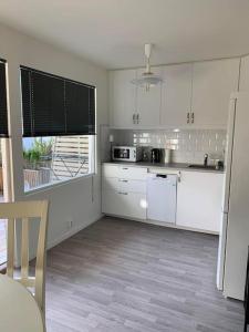 cocina con armarios blancos, mesa y silla en SylviaBo, en Skien