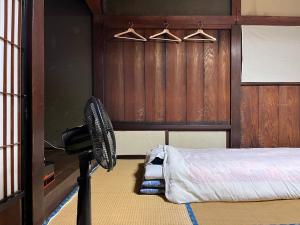 a room with a fan next to a bed at OSHI-KIKUYABO Mt-Fuji Historic Inn in Fujiyoshida
