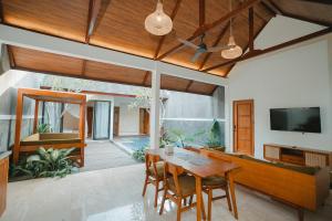 Villa Bulan Bali في جيمباران: غرفة طعام مع طاولة وكراسي خشبية