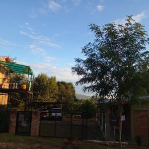 a tree in front of a house with a fence at Monoambiente amplio con pileta in Cosquín
