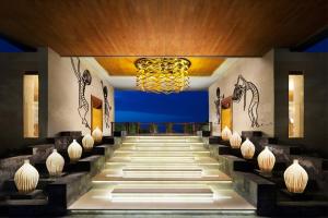 Le hall de l'hôtel est orné d'un lustre et d'escaliers. dans l'établissement Samabe Bali Suites & Villas, à Nusa Dua