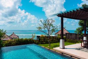 a swimming pool with a view of the ocean at Samabe Bali Suites & Villas in Nusa Dua