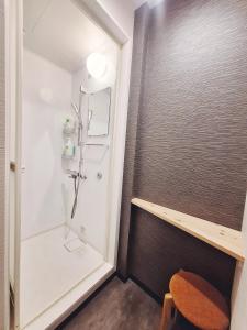 baño pequeño con ducha y encimera de madera en Poly Hostel Osaka, en Osaka