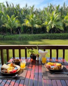 a table with two plates of food and orange juice at Hoi An Eco Lodge & Spa in Hoi An