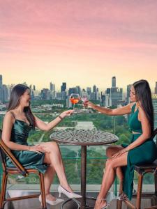dos mujeres sentadas en una mesa con una copa de vino en Column Bangkok Hotel, en Bangkok