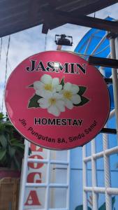 a sign for a restaurant with white flowers on it at Jasmin Homestay in Sanur