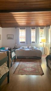 une chambre avec un grand lit et deux fenêtres dans l'établissement Casa do Fachoalto, à Petrópolis