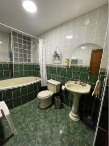 uma casa de banho com azulejos verdes, um WC e um lavatório. em FLAT AMOBLADO EN PUEBLO LIBRE - LIMA - PERÚ em Lima