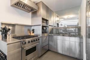 a stainless steel kitchen with a stove and a sink at Eden, dream high-end home in NYC in New York