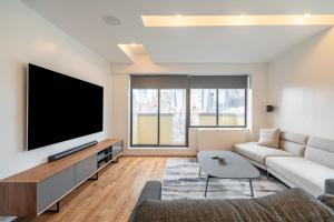 ein Wohnzimmer mit einem Flachbild-TV und einem Sofa in der Unterkunft Eden, dream high-end home in NYC in New York