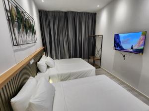 a hotel room with two beds and a flat screen tv at One Point Hotel in Kuching