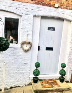 a white garage door with two potted trees in front of it at The Old Stable in Shifnal