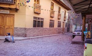 a boy sitting on a cobblestone street next to a building at CASA ESTEVES in Ollantaytambo