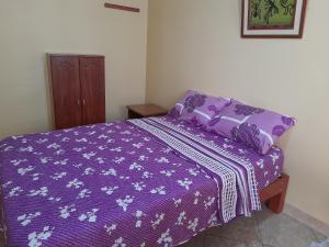 uma cama com um cobertor roxo e almofadas em Nasca Trails B&B em Nazca