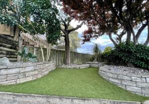 un patio con una pared de piedra y árboles en Breezy Ocean - The perfect getaway, en Mount Maunganui