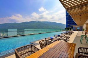 a swimming pool with tables and chairs on a building at Anya Premier Hotel Quy Nhon in Quy Nhon