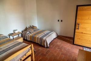 a bedroom with two beds and a wooden door at Casa Cecilia Lodging House in Oaxaca City