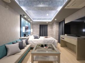 Habitación con cama, sofá y TV. en ホテル シードット 横浜 トレ, en Yokohama