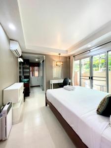 1 dormitorio con 1 cama blanca grande y escritorio en Hub53 Coliving Space, en Chiang Mai
