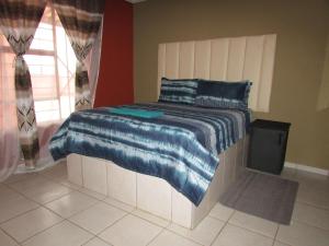 a bedroom with a bed with a blue blanket on it at Cozy Queen-Bed Apartment in Hammanskraal 