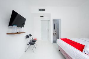 a white bedroom with a bed and a tv at RedDoorz near Jalan Cikini in Jakarta +20 photos