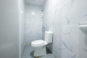 a white bathroom with a toilet and a sink at RedDoorz near Jalan Cikini in Jakarta