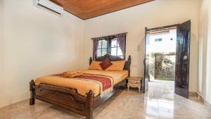 um quarto com uma cama num quarto com uma janela em Amel House Ubud em Ubud
