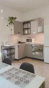 una cucina con mobili bianchi, tavolo e sedie di All'ombra dell'ulivo a Monopoli