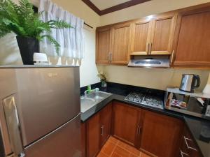 eine Küche mit Holzschränken und einem Kühlschrank aus Edelstahl in der Unterkunft Luxury 1 BR Suite Malarayat Lipa in Lipa