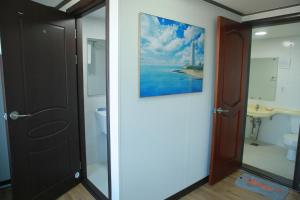 a bathroom with a toilet and a painting on the wall at Mangsang Beach Pension in Gangneung