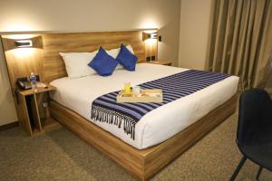 a hotel room with a large bed with blue pillows at Hotel San Francisco Tlaxcala in Tlaxcala de Xicohténcatl