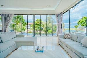 Elle comprend un salon doté d'un mobilier blanc et de grandes fenêtres. dans l'établissement Oasis Villa, à Đà Nẵng