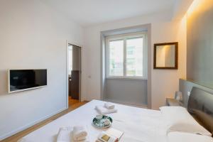 a white living room with a couch and a tv at Splendid house Buenos Aires Piazza Lima in Milan