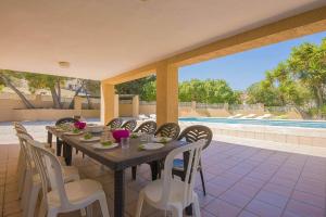 a dining table and chairs on a patio with a pool at Villa Bernia - PlusHolidays in Moraira