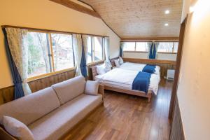 a bedroom with a bed and a couch and windows at KuDo's Lodge - Vacation STAY 85093 in Chikuni