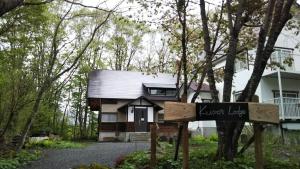 una pequeña casa con un cartel delante en KuDo's Lodge - Vacation STAY 85093, en Chikuni