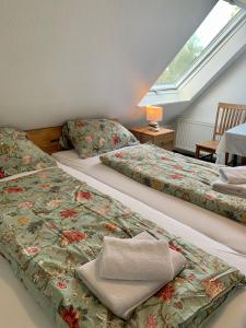 two beds in a room with a window at Hotel Pension Schienfatt am Dornumersieler Tief in Dornum