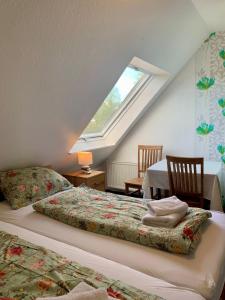 a attic bedroom with two beds and a window at Hotel Pension Schienfatt am Dornumersieler Tief in Dornum
