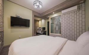 a bedroom with a white bed and a flat screen tv at B-Bas Hotel in Daegu
