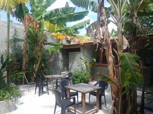 a patio with tables and chairs and a palm tree at Suffix Retreat in Fuvahmulah