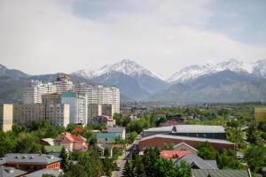 a city with snow capped mountains in the background at Mega Tower Almaty with beautiful moutain views in Almaty