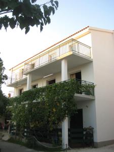 a white building with a balcony and a tree at Apartment Kosor in Zaboric
