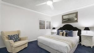 a white bedroom with a bed and a chair at Cumbernauld #20 Ocean Views, Wifi Accom Holidays in Terrigal
