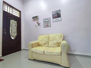 einen gelben Stuhl in einem Zimmer mit Tür in der Unterkunft NikNa Homestay Batu Rakit - WIFI in Kampong Ru Tujoh